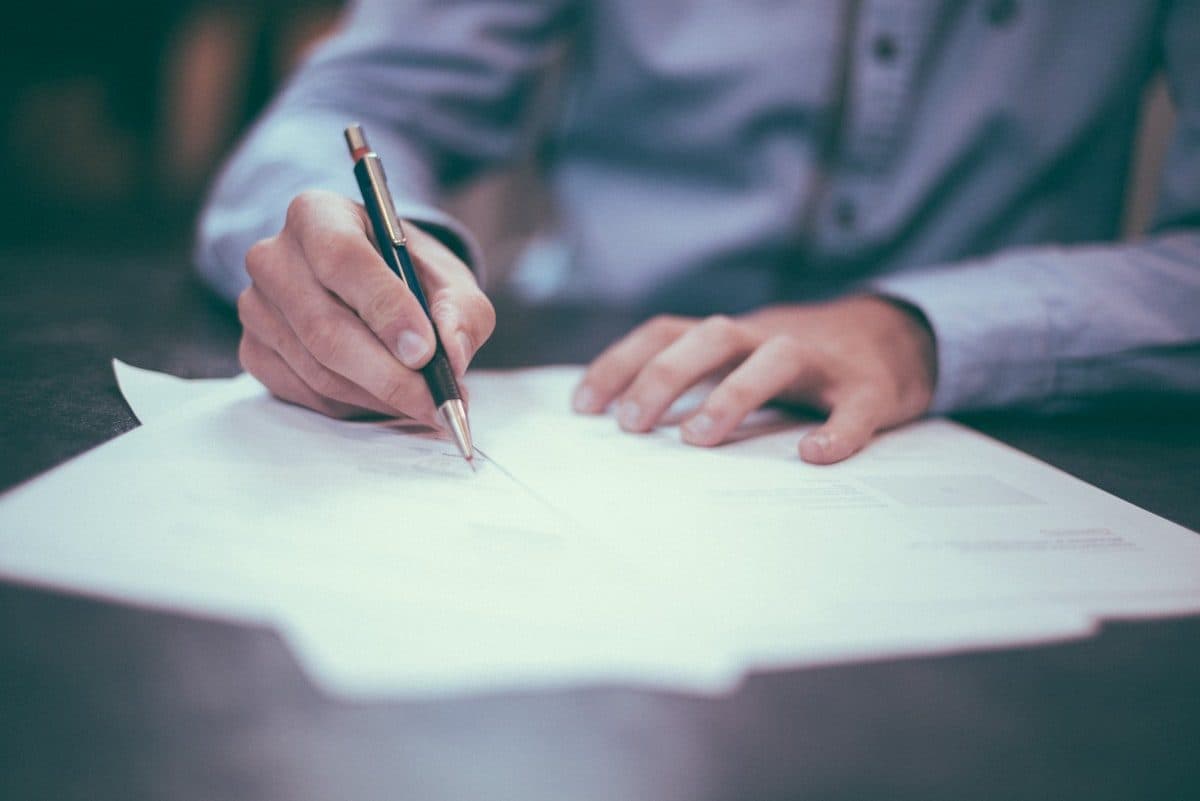 Hands reviewing documents with a pen — check before you pay